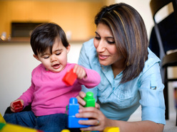 One-year-old girl and mum playing together with building blocks
