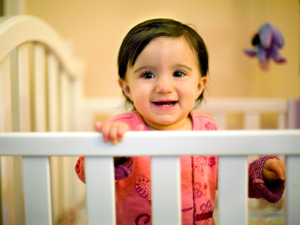 Smiling toddler standing up in their cot