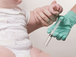 baby receiving vaccination in thigh by gloved hand