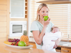 a mum holding her baby while eating an apple