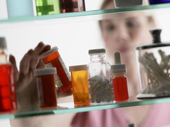 woman reaching into her medicine cabinet to get her fertility drugs