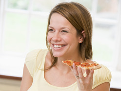 smiling pregnant woman eating pepperoni pizza
