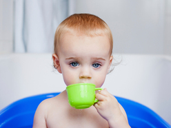 A toddler holding a green cup