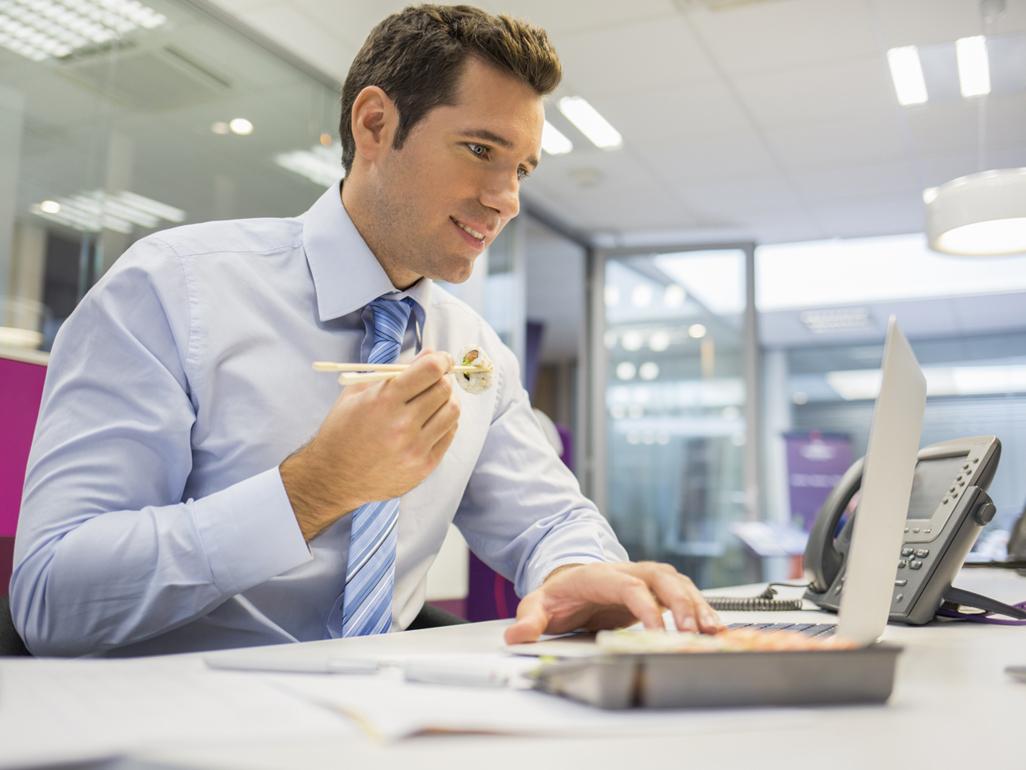 man at his office desk eating healthy food