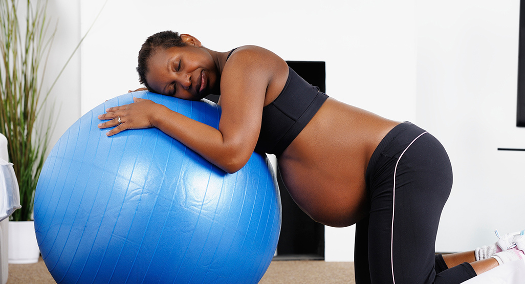 pregnant woman hugging a blue exercise ball