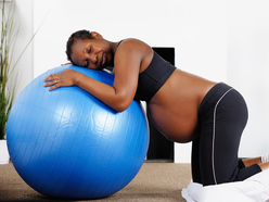 pregnant woman hugging a blue exercise ball