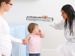 Mum with toddler getting weighed by doctor