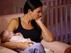 fed-up woman holding a baby in front of a cot