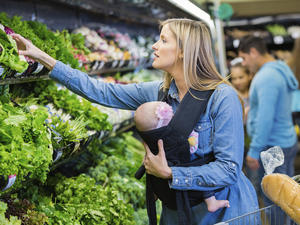 woman doing the grocery shopping with a baby in a carrier