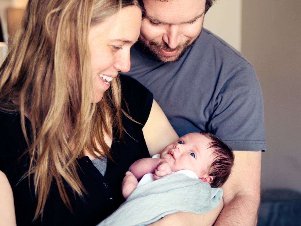 smiling man and woman holding newborn baby