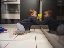 crawling baby exploring an open kitchen cabinet