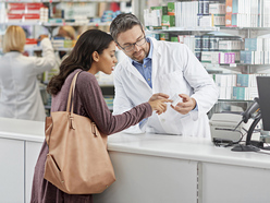 woman discussing instructions on a medicine packet with a pharmacist in a pharmacy