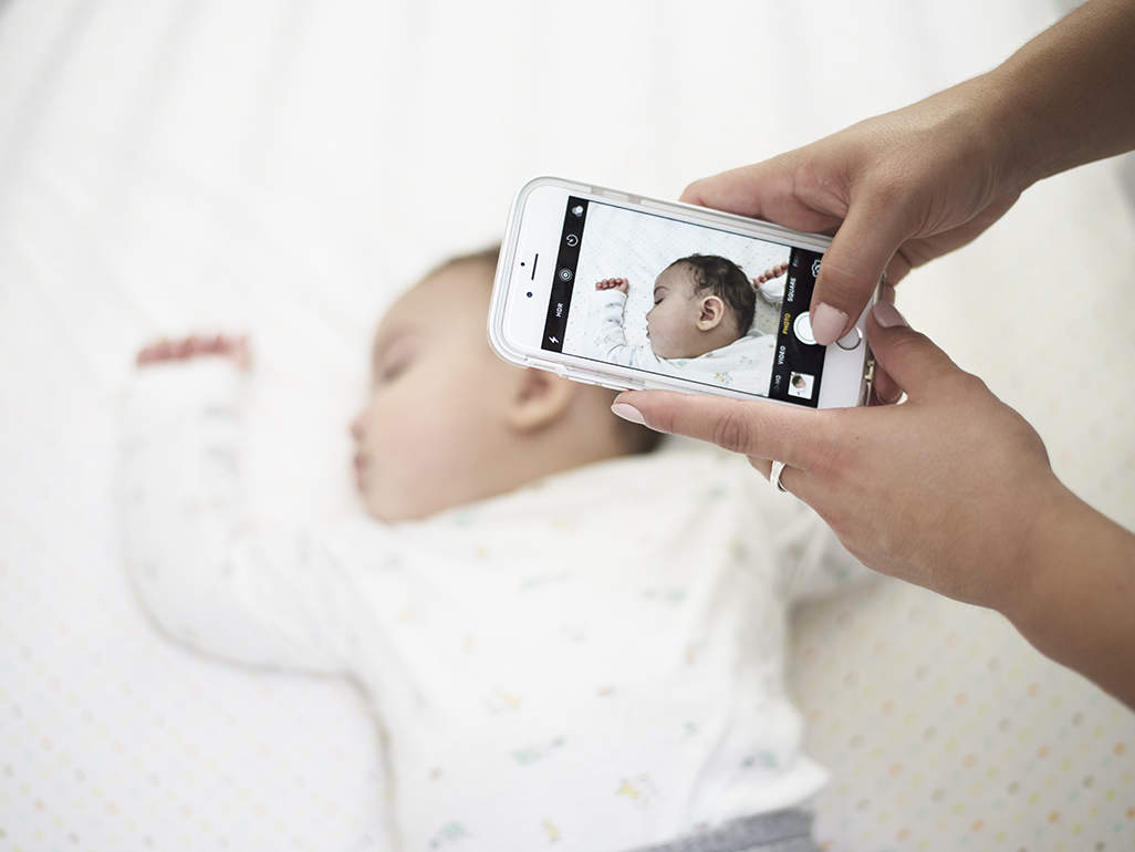 mother taking a picture of her baby with a cellphone