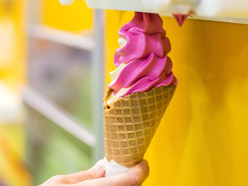pink and white soft-serve ice cream being dispensed into a waffle cone
