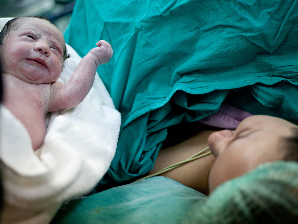 A woman meeting her newborn baby in theatre