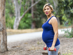 pregnant woman going for a brisk walk outside with weights in her hands