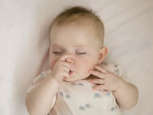 A baby sucking their thumb while sleeping