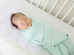 Sleeping newborn swaddled in a crib