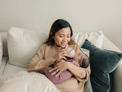 Woman sitting on a sofa feeding baby