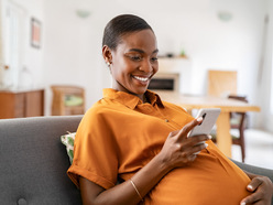 Pregnant woman smiling and looking at phone
