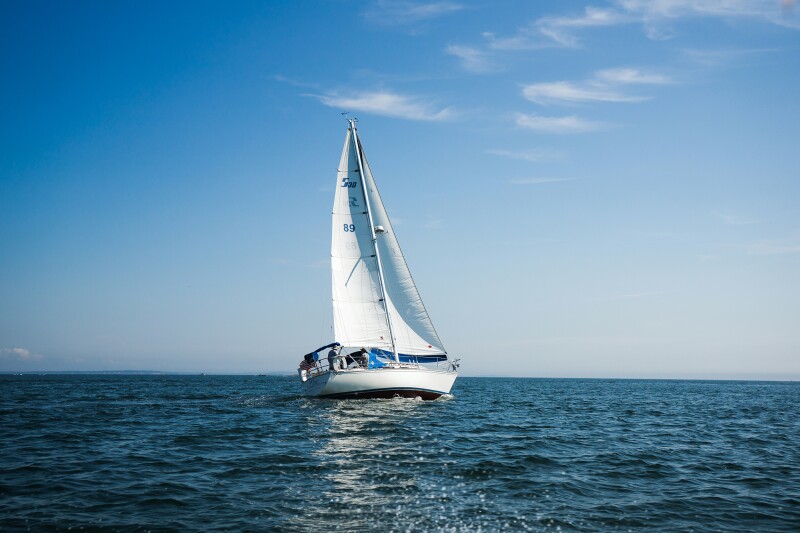 Das Foto zeigt eine malerische Szene auf dem Meer: ein Segelboot vor blauem Himmel. 