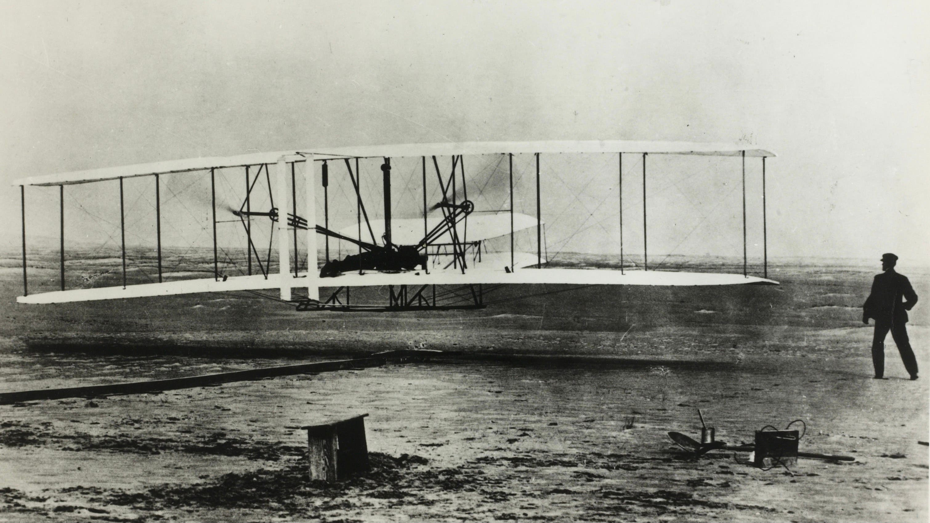 December 17th, 1903, Kittyhawk, North Carolina: The World&#039;s first flight with Orville Wright at the controls. His brother Wilbur is running at the side of the machine.