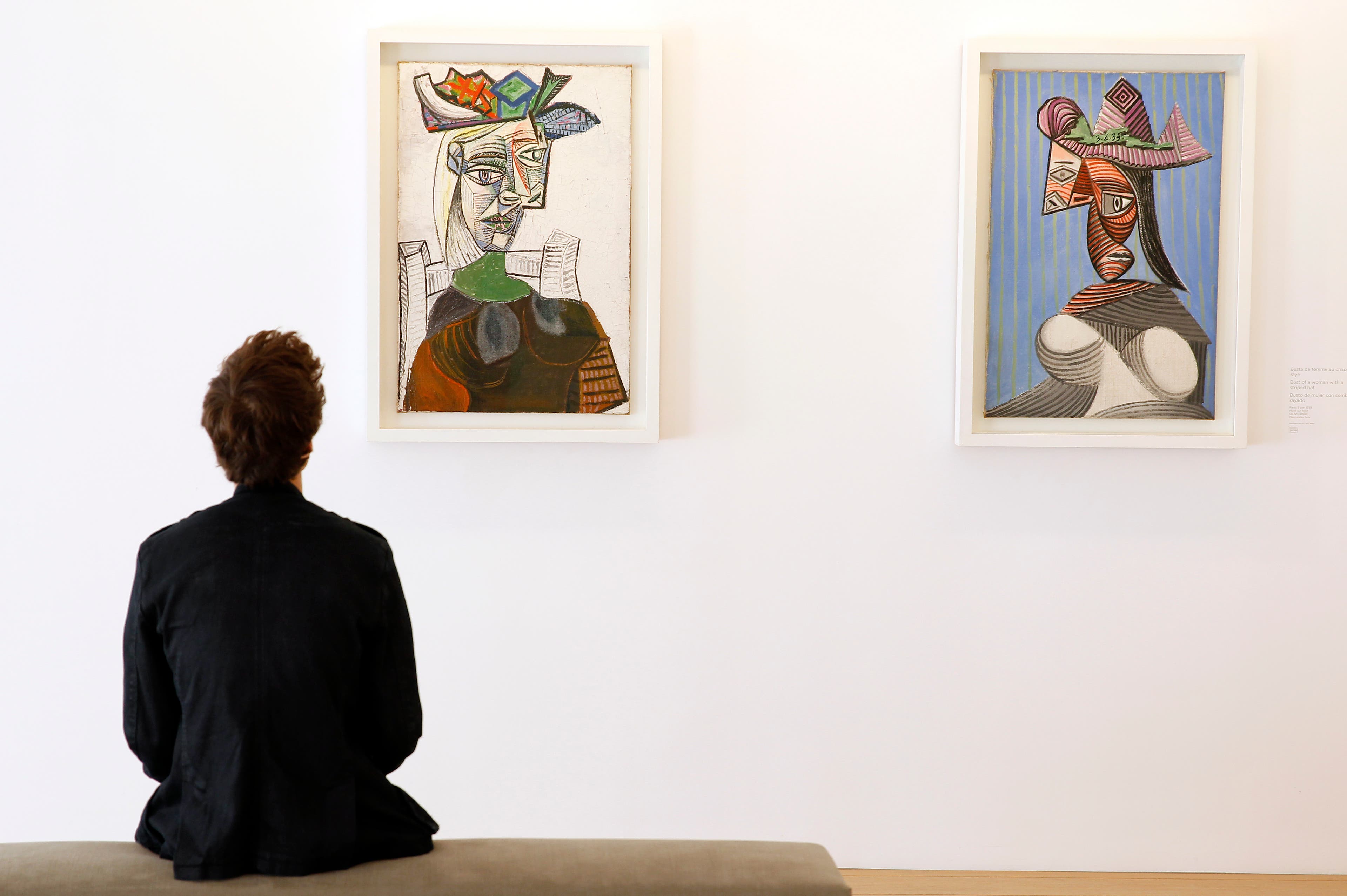PARIS, FRANCE - OCTOBER 18: A visitor looks at Picasso paintings 'Seated woman with a hat' and 'Bust of a woman with a striped' during the press day at the Picasso Museum, on October 18, 2014 in Paris, France. The museum will reopen on the 25th and will be inaugurated the same day by French president Francois Hollande. (Photo by Thierry Chesnot/Getty Images)