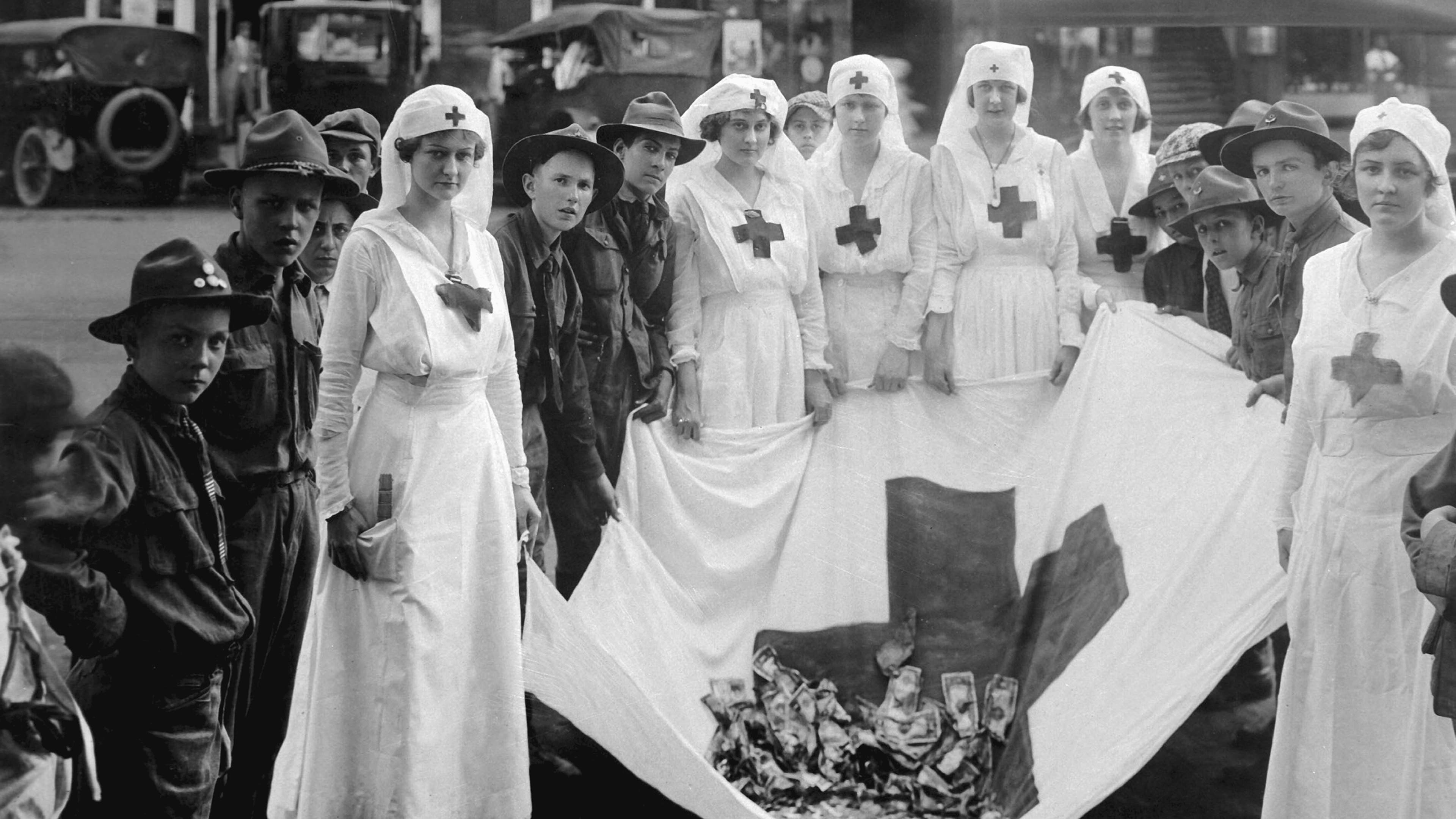 Group portrait of female American Red Cross workers with uniformed young boys (possibly boy scouts) with a Red Cross flag holding money, during a Red Cross parade, Birmingham, Alabama, May, 1918. US War Department photo.