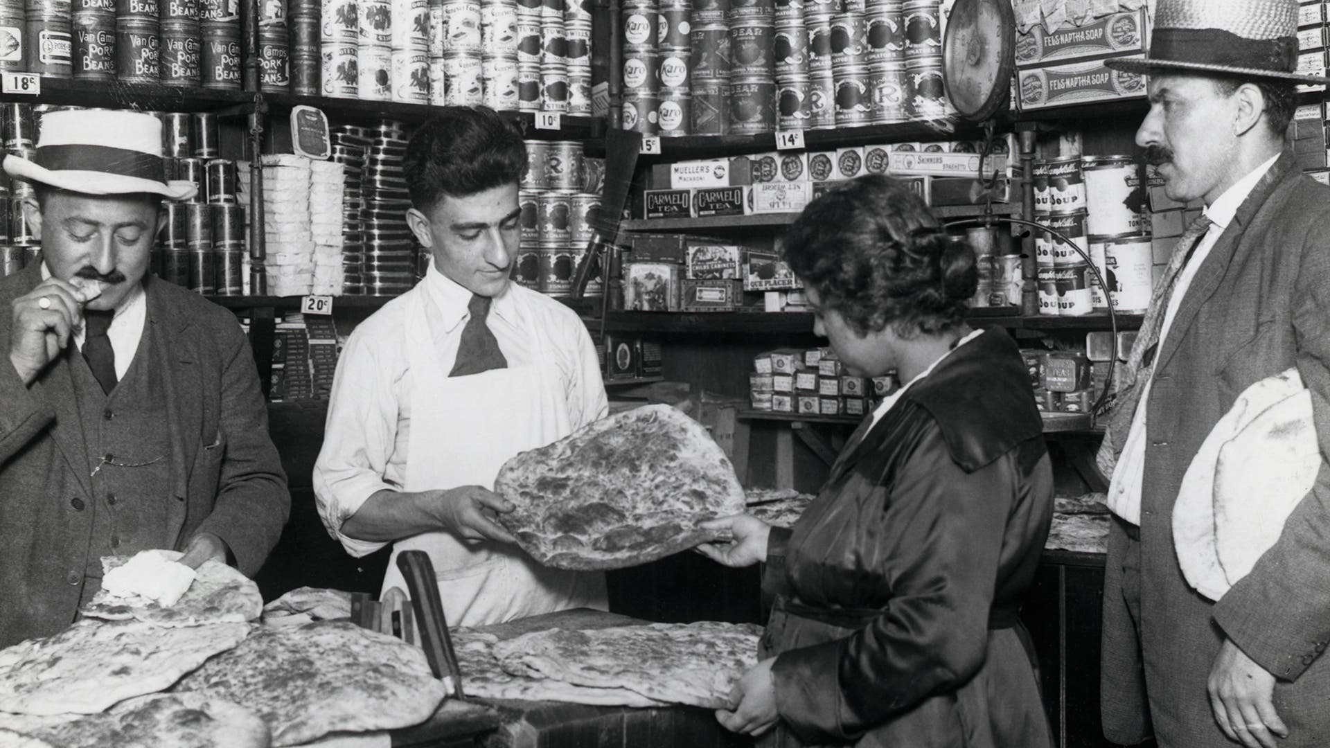 Interior view of a Syrian shop showing customers buying marcouck, circa 1919.