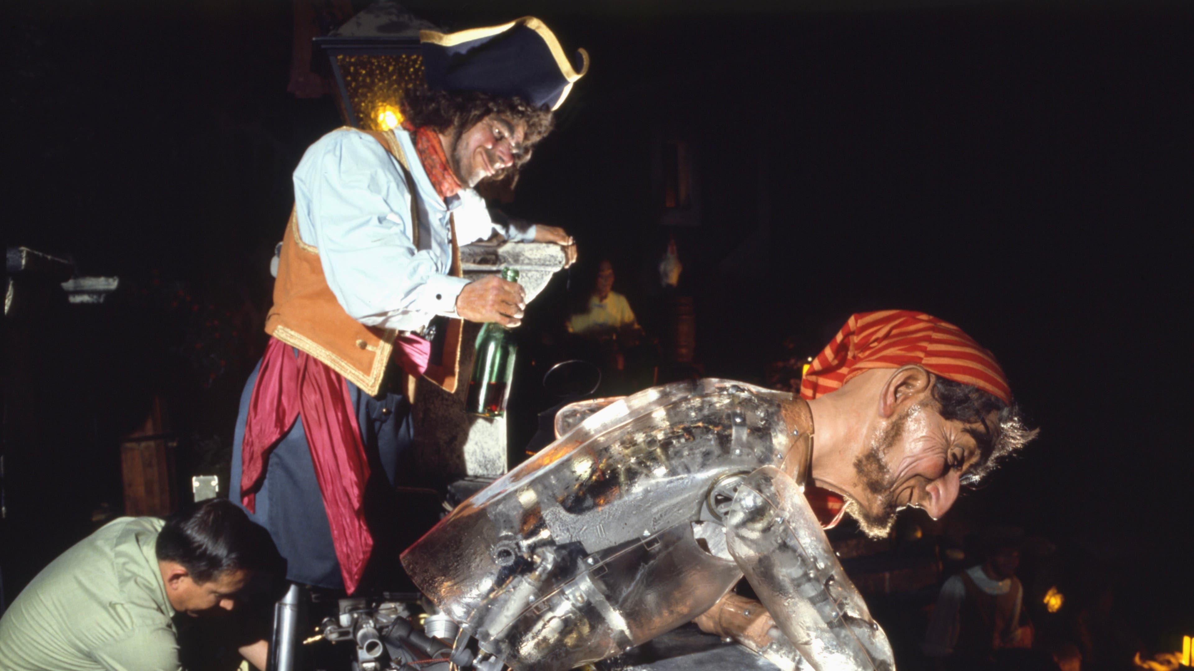 Animatronic pirate figures with realistic looking heads and robotic bodies lean over to be seen by visitors to Disney's Pirates of the Caribbean ride