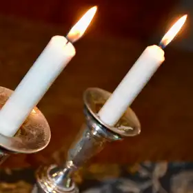 Two lit shabbat candles in silver candlesticks
