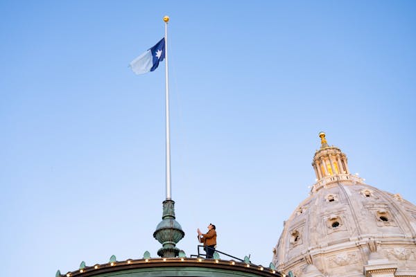 Grounds supervisor Charlie Krueger raises the new Minnesota state flag for the first time at sunrise atop the Minnesota State Capitol in St. Paul on S