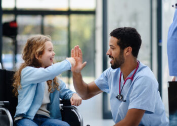 A doctor giving a child high five Description automatically generated