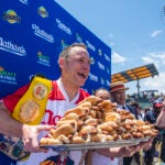 Winners Joey Chestnut and Michelle Lesco, obscured behind hot dogs, pose at the Nathan's Famous Fourth of July International Hot Dog-Eating Contest in Coney Island's Maimonides Park on Sunday, July 4, 2021, in the Brooklyn borough of New York.
