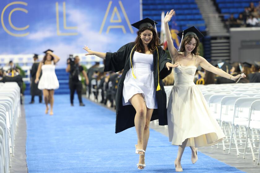 WESTWOOD CA JUNE 14, 2024 - Graduates Grace Shelby Roemer, left, and Guinivere Kimber, dance down the aisle as commencement ceremonies are underway at UCLA, where they will be conferring a total of 10,000 bachelor's degrees and 5,000 graduate degrees. (Christina House / Los Angeles Times)