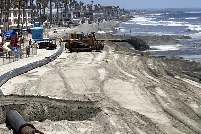 Sand dredged from the Oceanside harbor is pumped onto the beach south of the pier Wednesday.