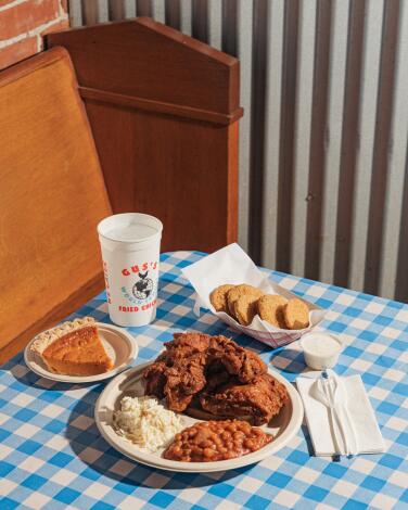 A meal of fried chicken, sides and pie on a table with a blue and white checked tablecloth