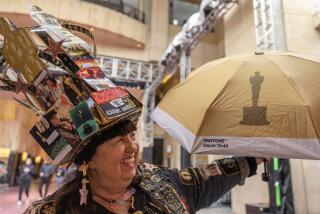 HOLLYWOOD, CA- MARCH 06: Vivianne Robinson, who calls herself 'Oscars Super Fan,' visits the preparations under way at the Dolby Theatre in Hollywood, CA on Wednesday, March 6, 2024. On her hat are the 'Best Picture' nominees. She has been dressing up and coming by since 2007. (Myung J. Chun / Los Angeles Times)