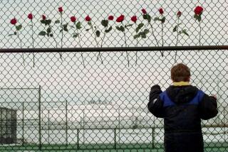 FILE - In this April 24, 1999 file photo a boy looks through the fence at the Columbine High School tennis courts in Littleton, Colo. Thirteen roses were placed on the fence in remembrance of the 13 people killed by two gun wielding students at the school, Tuesday, April 20, 1999. Classes are canceled Tuesday, April 20, 2010 at Columbine High School on the anniversary of the 1999 shootings. Twelve students and a teacher died in the shootings before two teenage gunmen committed suicide. (AP Photo/Eric Gay, File)