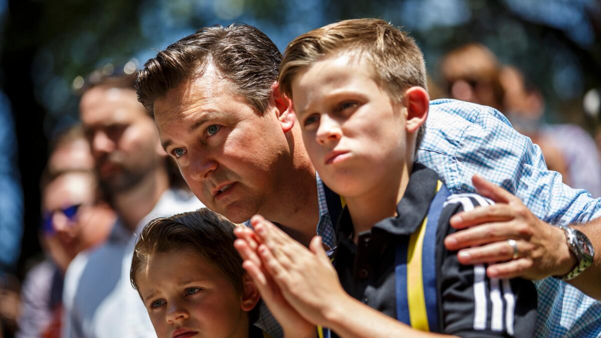 Ethan Boothe, center, talks to his sons Greyson Boothe, 8, left, and Austin Boothe, 10, right, attends an interfaith prayer service for the victims of the police shooting.