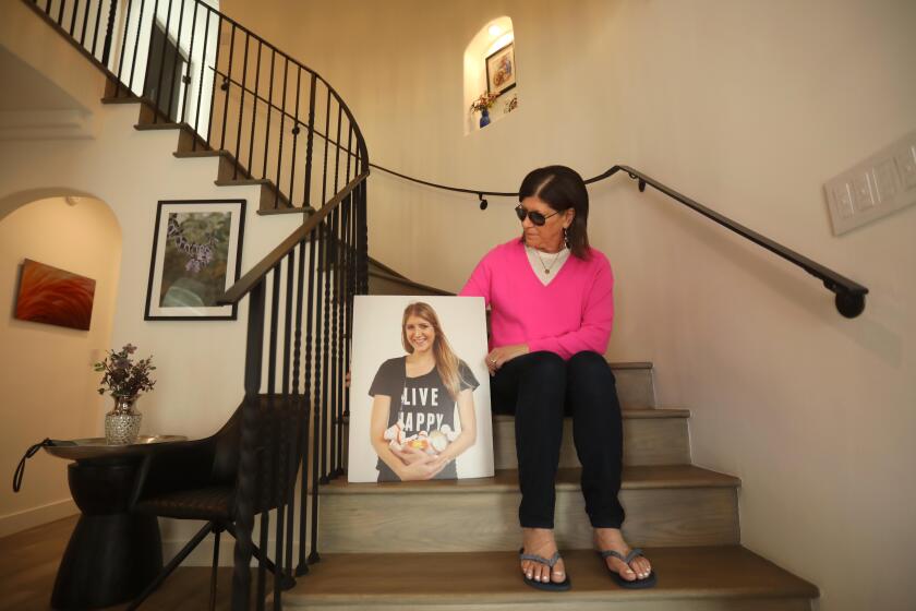 BEVERLY HILLS, CA - MAY 3, 2024 - Diane Shader Smith sits next to a portrait of her daughter Mallory Smith in her home in Beverly Hills on May 3, 2024. Mallory, who had been living with cystic fibrosis since she was a child, died at the age of 25 in 2017 of an antibiotic-resistant lung infection she contracted after a transplant. On Tuesday, May 7, Random House is publishing Mallory's diary entries during her illness as the book, "Diary of a Dying Girl,' and on the same day the WHO, CDC and a ton of other organizations are launching a website called the Global AMR Diary, where other people can share their stories of drug-resistant infections. Shader Smith has become a fierce advocate for awareness of antibiotic resistance. (Genaro Molina/Los Angeles Times)