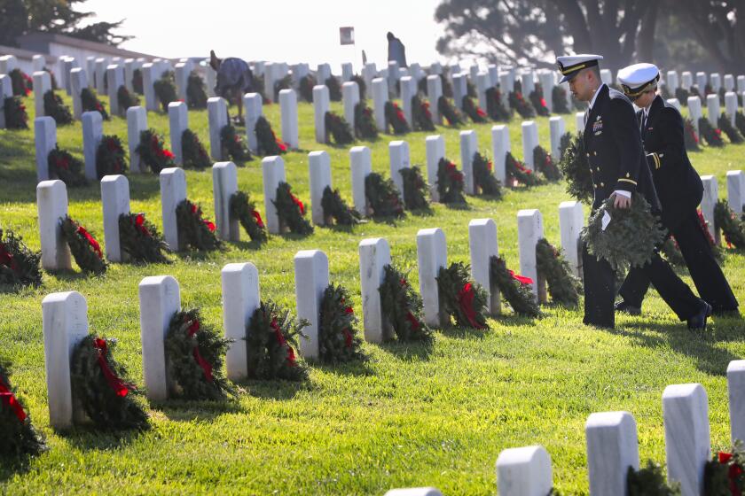 Navy Ensign Vu Chau and Lt. j.g. Alessa Andersen carry wreaths to headstones during the Wreaths Across America wreath laying event at Fort Rosecrans National Cemetery, December 14, 2019 in San Diego, California to honor veterans. Between 6,000 and 7,000 wreaths were placed at the headstones in Ft. Rosecrans, one of more than 1,600 locations throughout America, at sea and abroad receiving the wreaths during the event.