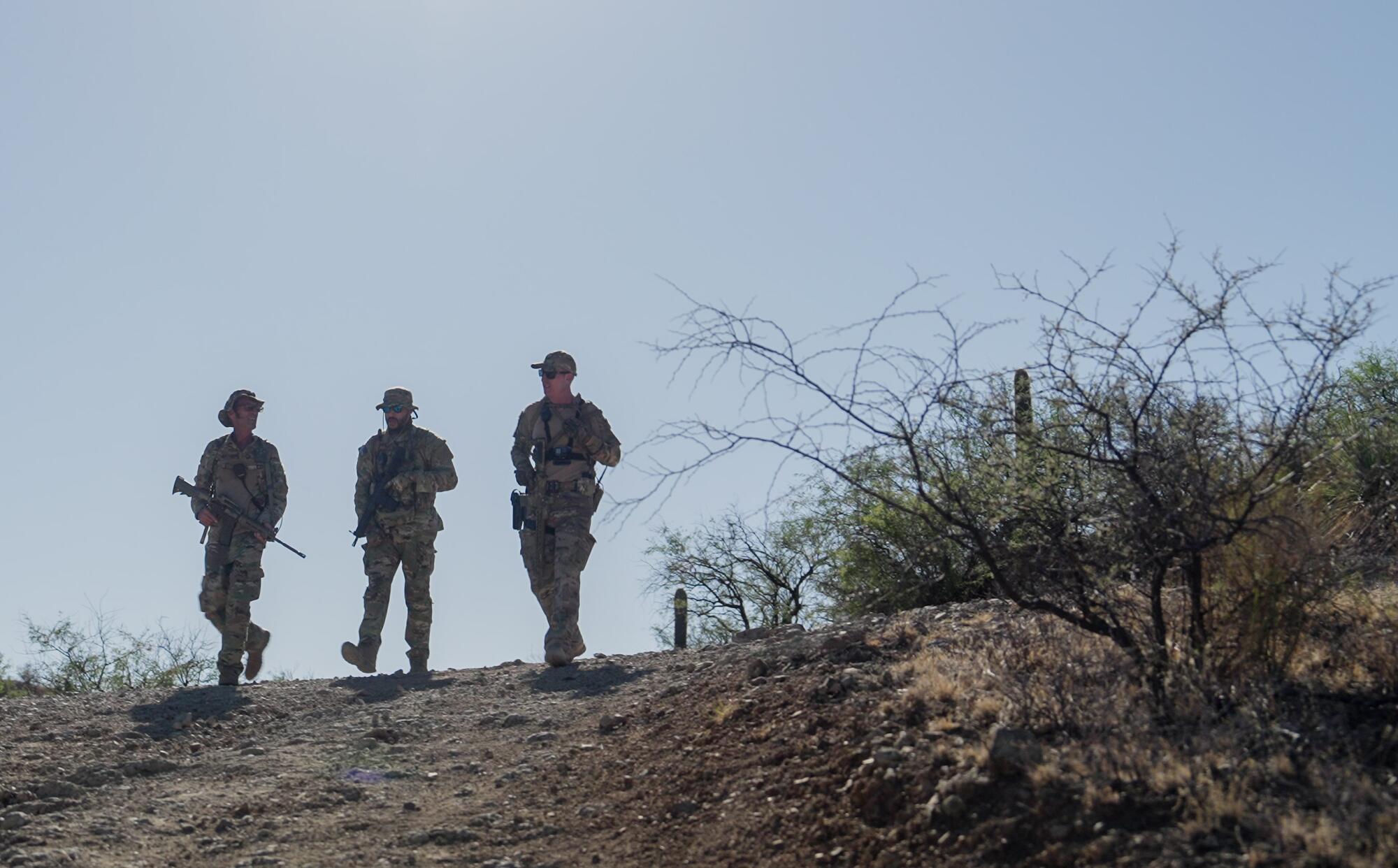 Three men walk in the desert near the U.S.-Mexico border