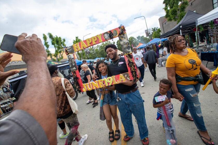 Leimert Park, CA - June 19: Leana Rice and Jaylen Rowe pose for a photo inside a Juneteenth frame as people gather at the Leimert Park Village Juneteenth Festival to enjoy food art and music on Monday, June 19, 2023 in Leimert Park, CA. (Brian van der Brug / Los Angeles Times)