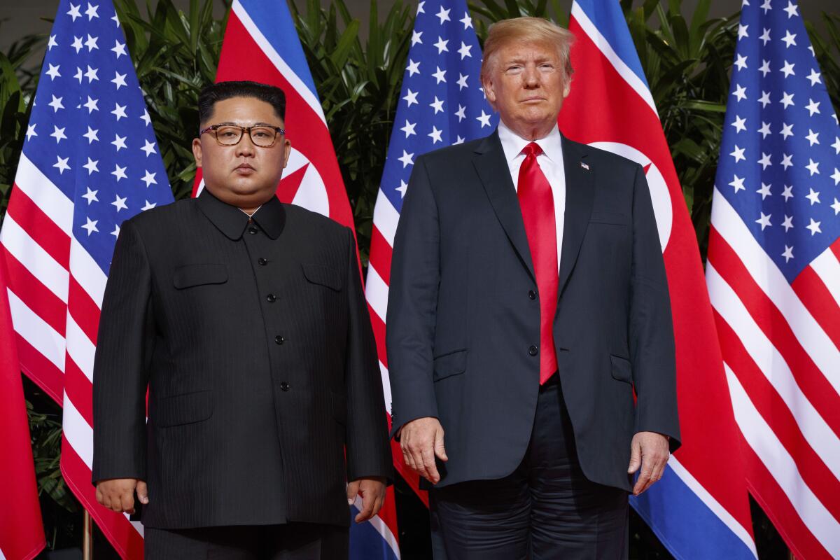 Kim Jong Un stands next to Donald Trump.