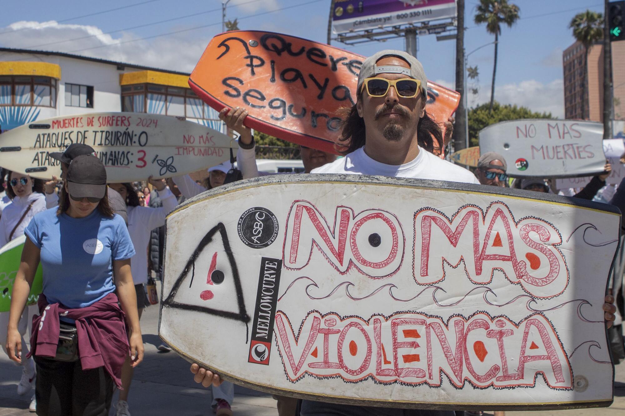 A demonstrator holding a bodyboard written in Spanish, "No more violence"
