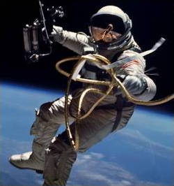 Astronaut Ed White space walking in a space suit with a gold-plated visor helmet.