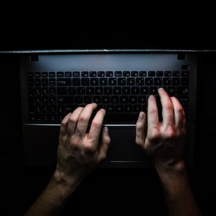 Hands on laptop in dark room