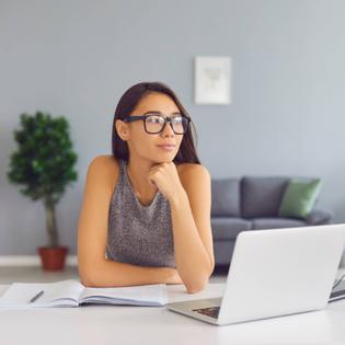 Woman thinking while sitting at her computer desk.