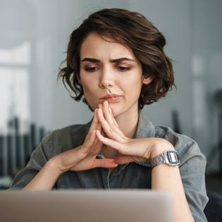Woman thinking while sitting in front of laptop.